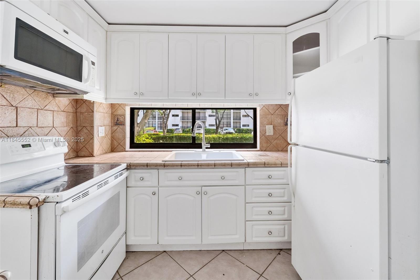 16919 North Bay Road, Unit 115 Sunny Isles Beach, FL 33160 - Photo 13 of 20 a kitchen with white cabinets and white appliances