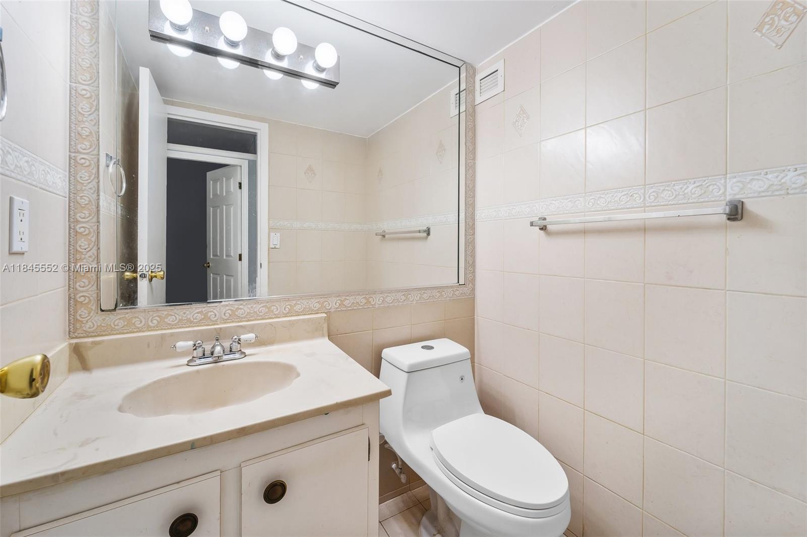 16919 North Bay Road, Unit 115 Sunny Isles Beach, FL 33160 - Photo 8 of 20 a bathroom with a granite countertop sink a toilet a mirror and shower