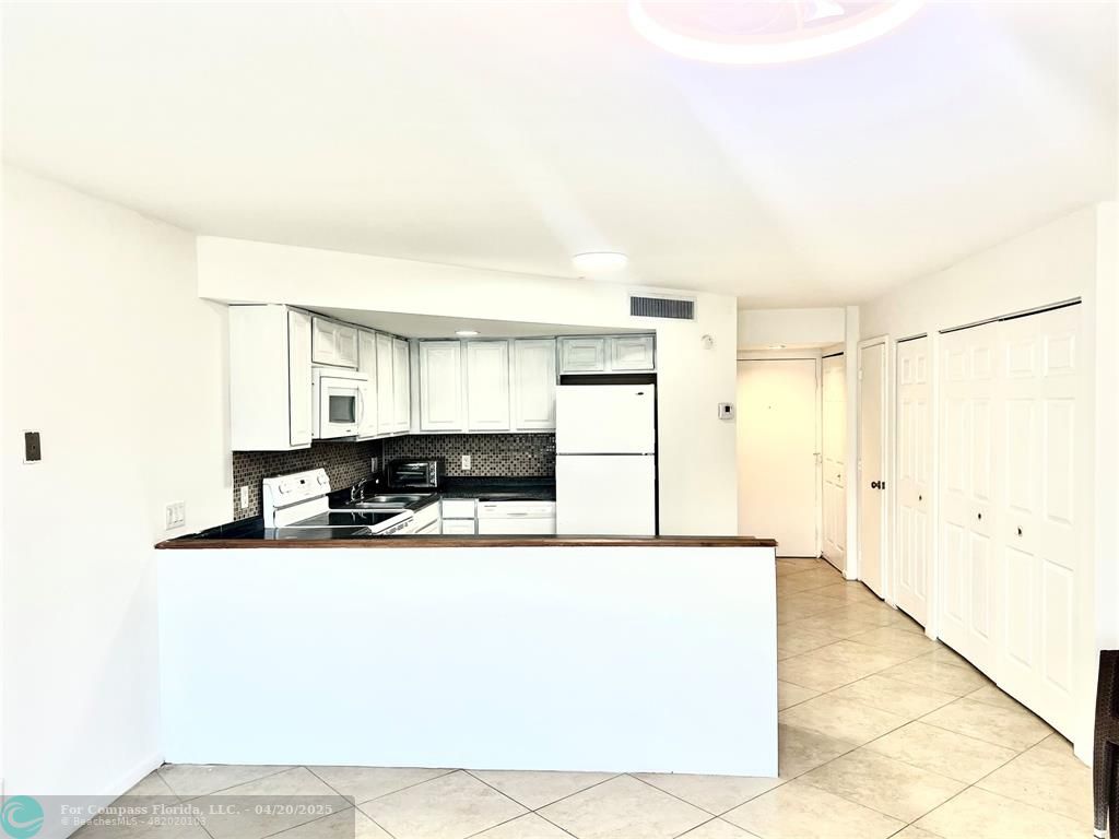 41 Deer Creek Road, Unit G106 Deerfield Beach, FL 33442 - Photo 1 of 3 a large white kitchen with kitchen island a sink a refrigerator and a stove