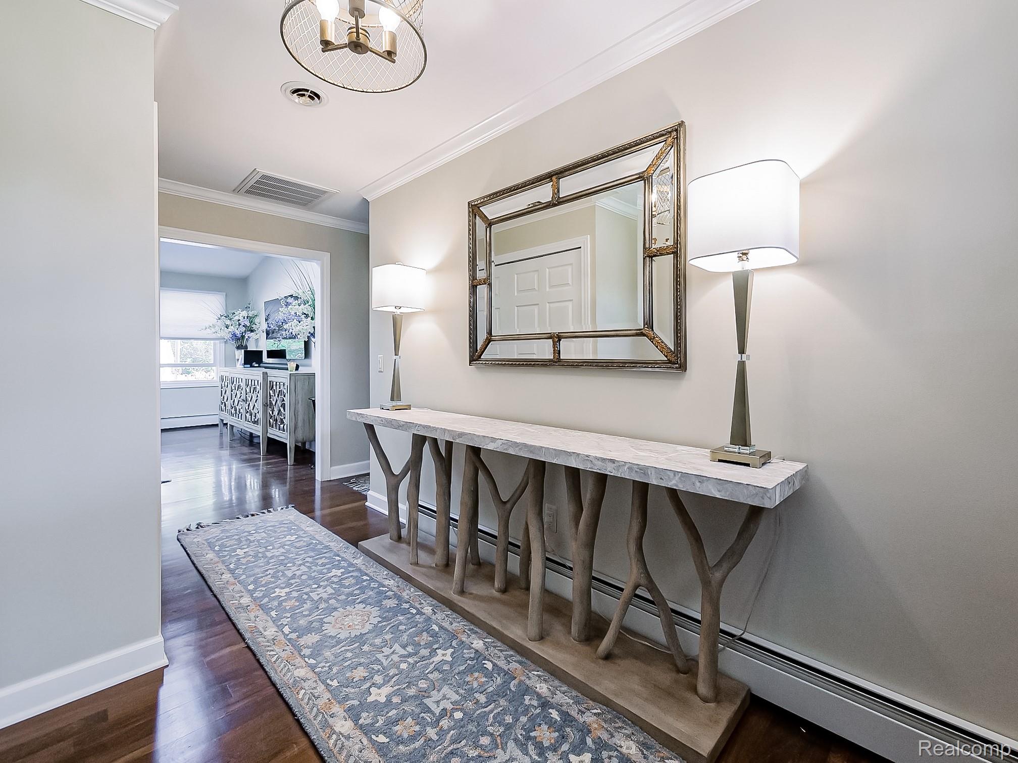 3720 East Clarkston Road Oakland, MI 48363 - Photo 11 of 60 Hallway with a baseboard radiator, ornamental molding, dark wood-style flooring, and suspended lighting