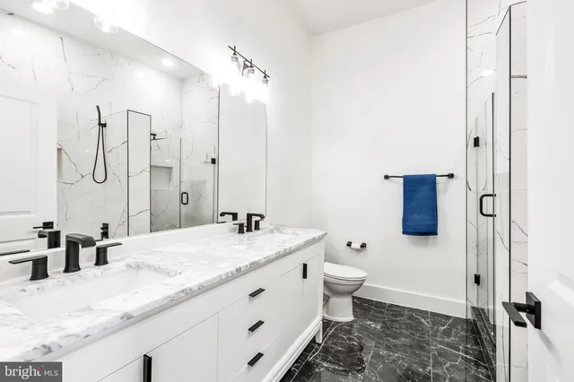 a bathroom with a granite countertop sink a toilet and shower