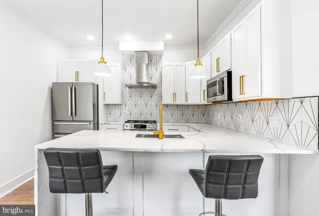 a kitchen with stainless steel appliances a sink a microwave a refrigerator and chairs