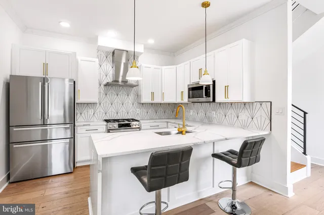 a kitchen with stainless steel appliances granite countertop a stove a refrigerator a oven a sink a dining table and chairs with wooden floor