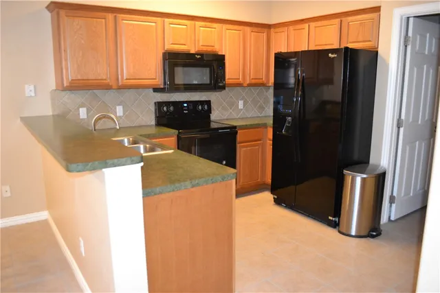 a kitchen with stainless steel appliances granite countertop a refrigerator a stove top oven a sink and dishwasher