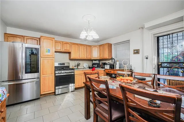 a kitchen with stainless steel appliances a refrigerator a stove a sink a dining table and chairs