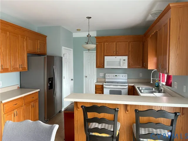 a kitchen with a refrigerator a stove a sink dishwasher and wooden cabinets with wooden floor