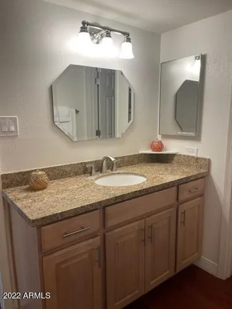 a bathroom with a granite countertop sink a large mirror and vanity
