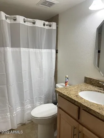 a bathroom with a granite countertop sink toilet and shower