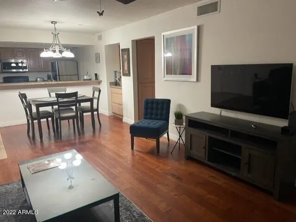 a living room with furniture a chandelier a flat screen tv and kitchen view