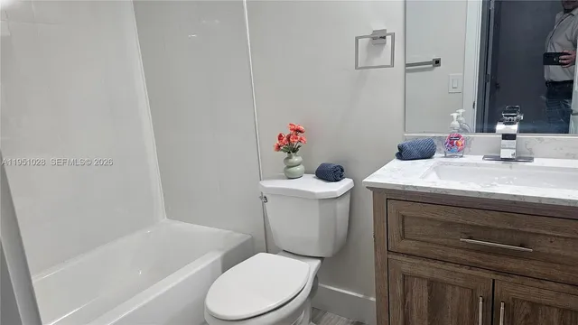 a white toilet sitting next to a bathroom sink and vanity