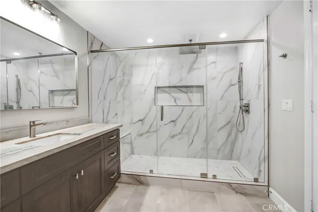 a bathroom with a granite countertop sink mirror and a shower