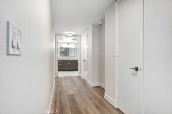 a view of a hallway with wooden floor and a kitchen