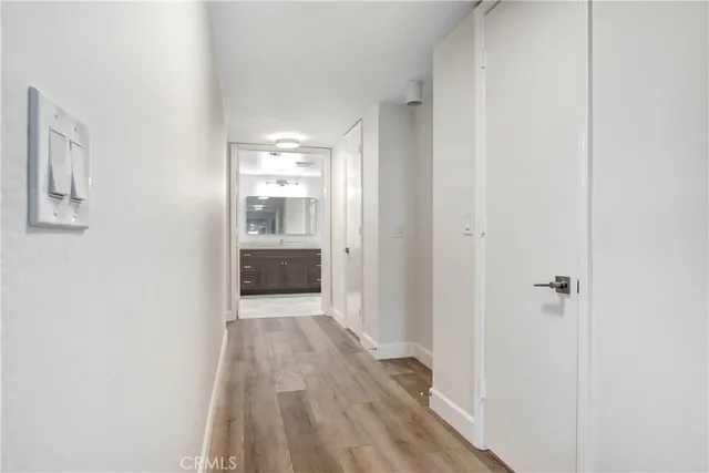 a view of a hallway with wooden floor and a kitchen