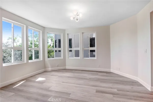 a view of an empty room with a window and wooden floor