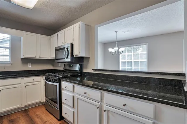 a kitchen with granite countertop white cabinets white appliances and a sink
