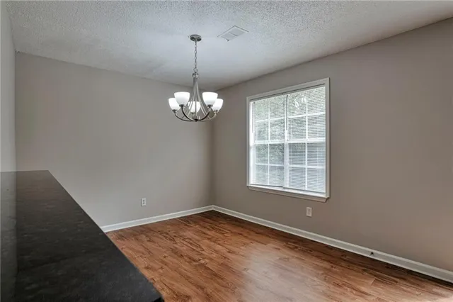 an empty room with wooden floor exposed radiator and windows