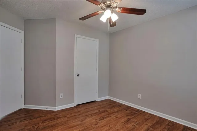 a view of an empty room with wooden floor and a chandelier fan