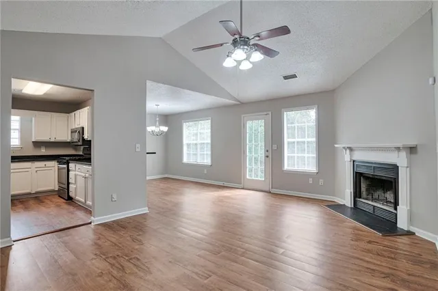 a view of an empty room with kitchen and a window