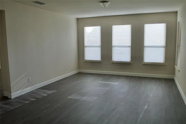 an empty room with wooden floor and windows