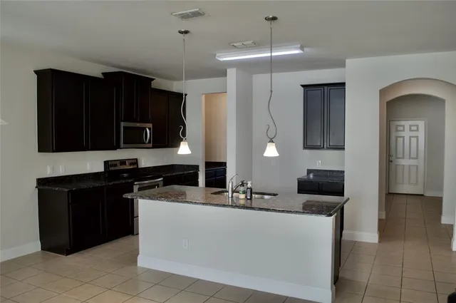 a kitchen with a sink a stove and black cabinets