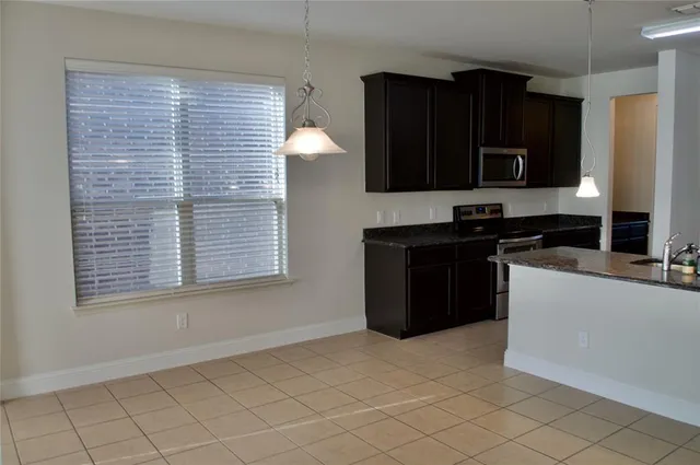 a view of an empty room with window and chandelier fan