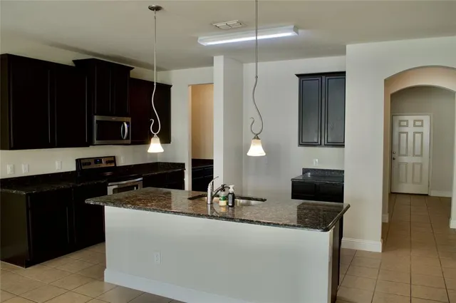 a kitchen with stainless steel appliances granite countertop a sink and a stove top oven with wooden floor