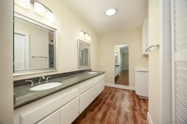 a bathroom with a granite countertop double vanity sink and mirror