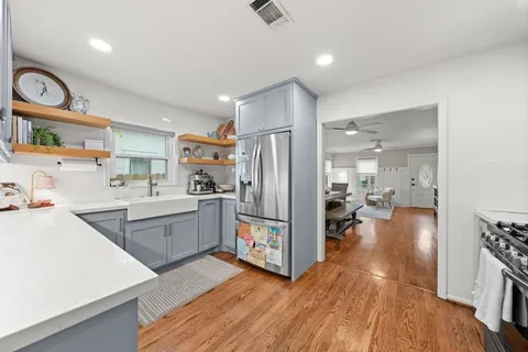a kitchen with granite countertop a stove top oven a sink dishwasher and cabinets with wooden floor