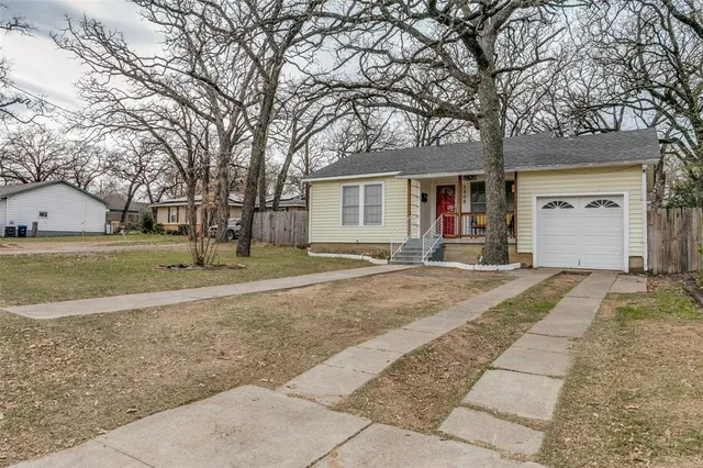 a view of a house with a yard and large tree