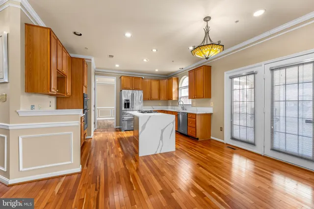 a kitchen with stainless steel appliances granite countertop a refrigerator a sink dishwasher a stove and white countertops with wooden floor