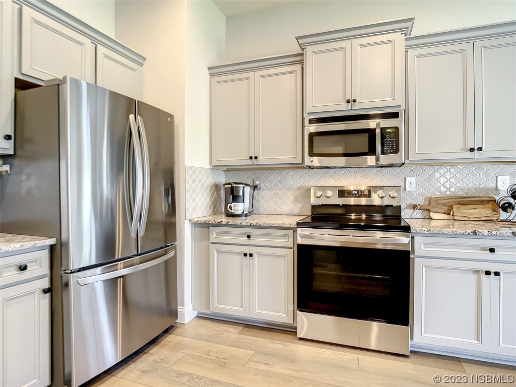 512 Coral Trace Boulevard Edgewater, FL 32132 - Photo 8 of 45 a kitchen with stainless steel appliances white cabinets white stove a refrigerator and a microwave