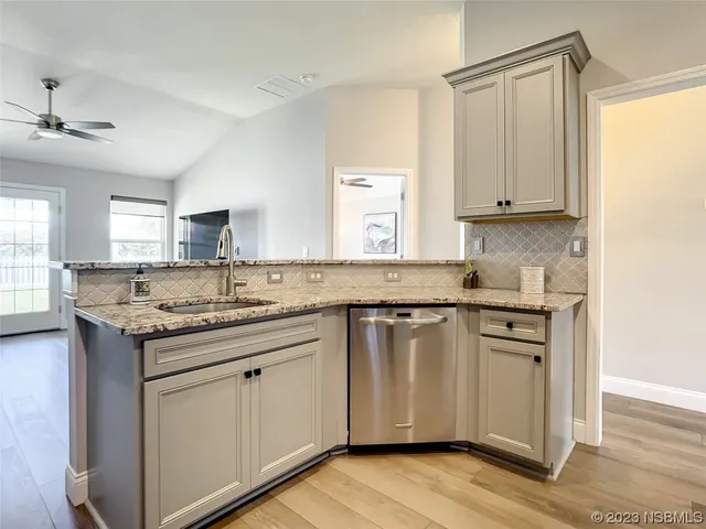 a kitchen with stainless steel appliances granite countertop a sink and cabinets with wooden floor