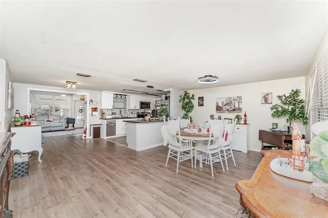a dining room with kitchen island wooden floor and view kitchen