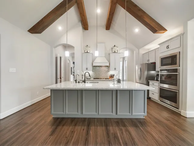 a large kitchen with stainless steel appliances a large counter space and wooden floor