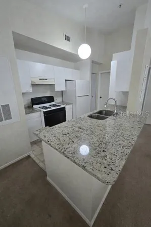 a kitchen with kitchen island granite countertop a sink stove and refrigerator