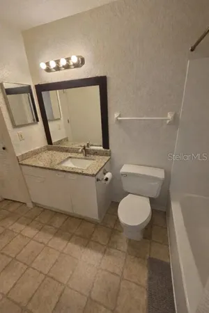 a bathroom with a granite countertop toilet sink and mirror