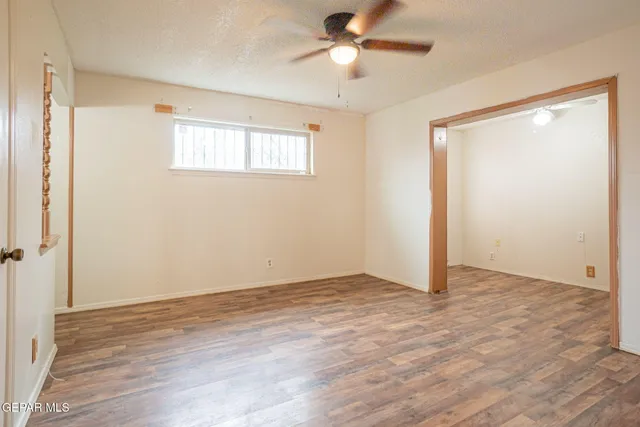 a view of an empty room with window and wooden floor