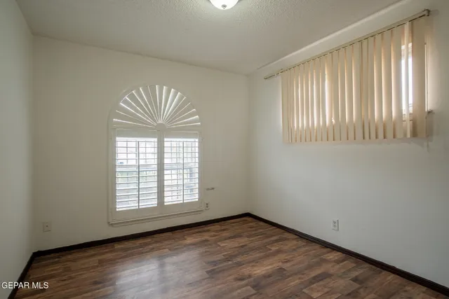 a view of an empty room with wooden floor and closet