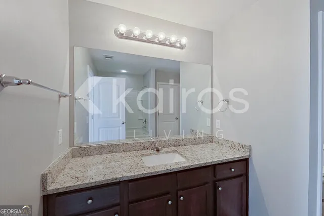 a bathroom with a granite countertop sink a large mirror and vanity
