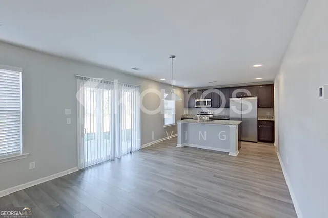 a kitchen with stainless steel appliances granite countertop a refrigerator a sink dishwasher a stove and white countertops with wooden floor