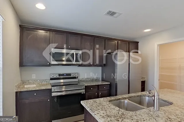 a kitchen with stainless steel appliances granite countertop a sink and a refrigerator
