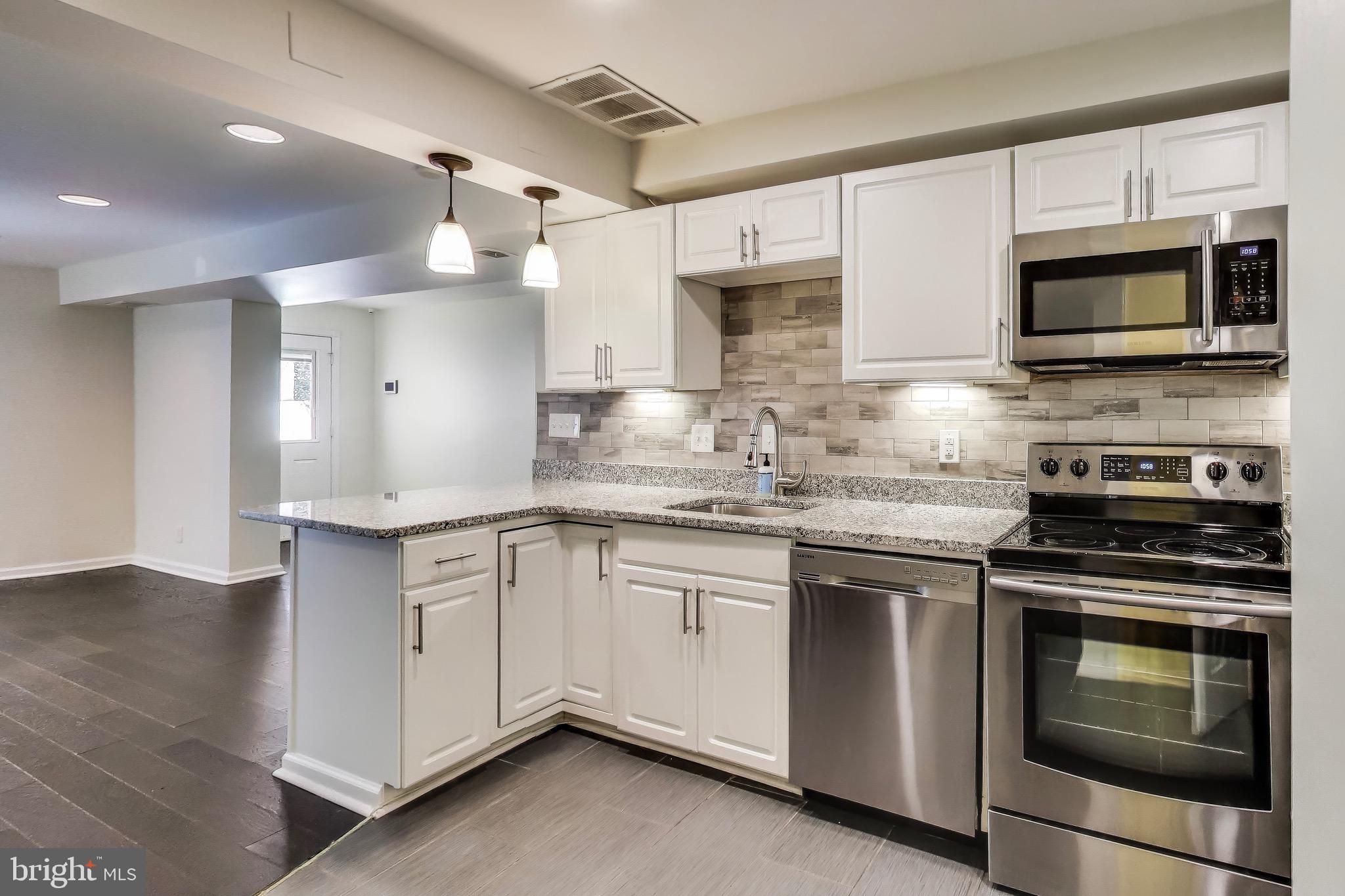 1625 S Street Northwest, Unit 1 Washington, DC 20009 - Photo 2 of 13 a kitchen with stainless steel appliances granite countertop grey cabinets a stove a sink and a microwave