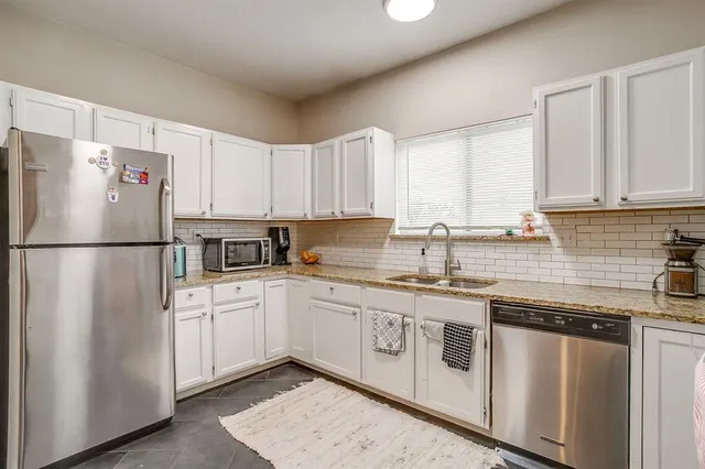 a kitchen with stainless steel appliances granite countertop a refrigerator a stove a sink and white cabinets
