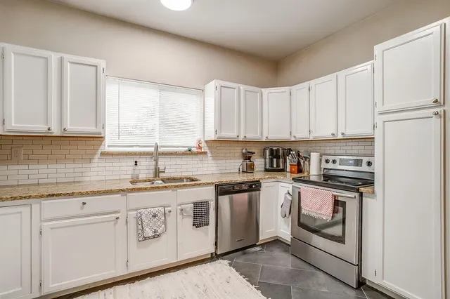 a kitchen with stainless steel appliances granite countertop a stove a sink and white cabinets