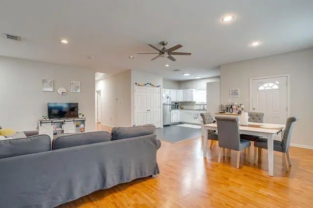 a living room with furniture kitchen view and a wooden floor