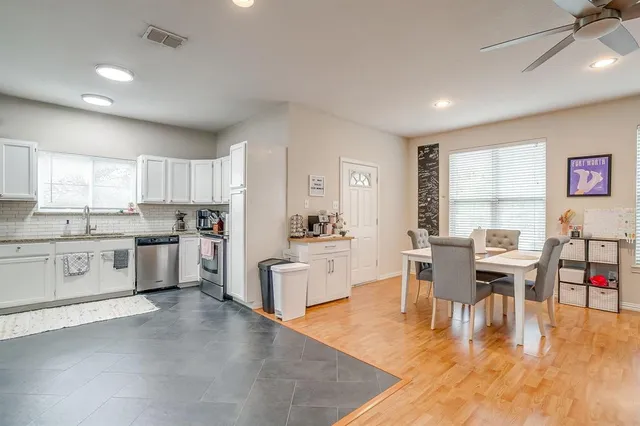 a large kitchen with white cabinets and wooden floor