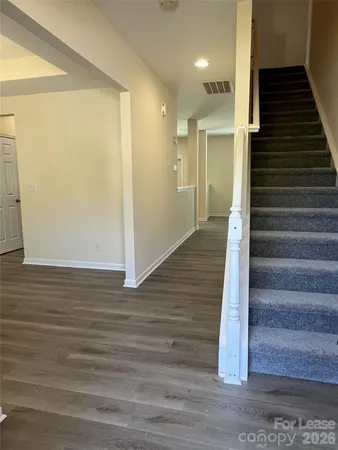 a view of a hallway with wooden floor and staircase