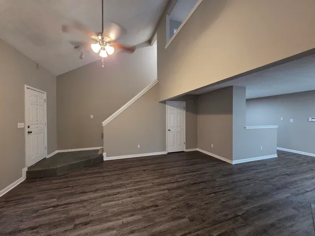 a view of an empty room with wooden floor and chandelier