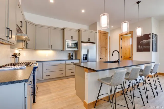 a kitchen with stainless steel appliances granite countertop a sink a stove a refrigerator and cabinets