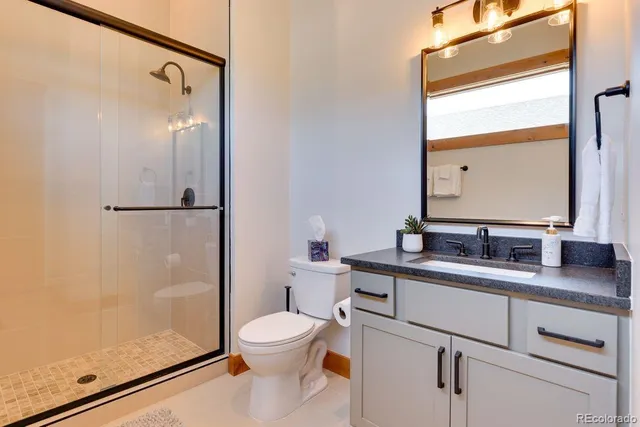 a bathroom with a granite countertop sink mirror vanity and toilet